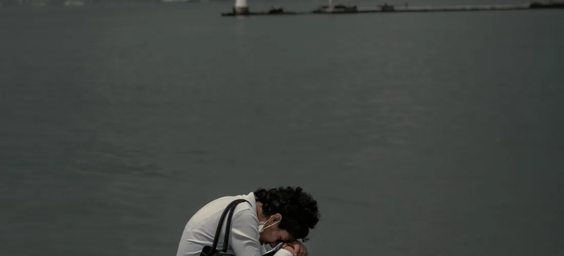 Una persona sentada sobre unas rocas junto al mar, en un momento de calma